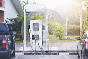 Car charging station in front of a green flowering background