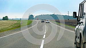 Car chase on asphalt countryside road winding through the fields