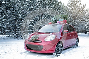 Car with Christmas tree, wreath and gifts in snowy forest