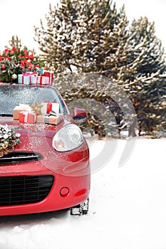 Car with Christmas tree, wreath and gifts in snowy forest