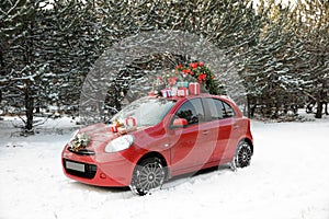 Car with Christmas tree, wreath and gifts in snowy forest