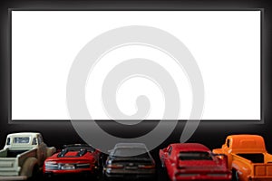 Car cinema,drive-in, with several five pickup truck type toy cars,back view,large white blank screen in front of them