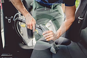 Car cleaning - male using professional steam vacuum for dirty car interior