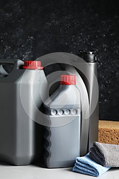 Car cleaning products, canisters with motor oil and microfiber fabric on light grey table