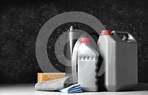 Car cleaning products, canisters with motor oil and microfiber fabric on light grey table. Space for text