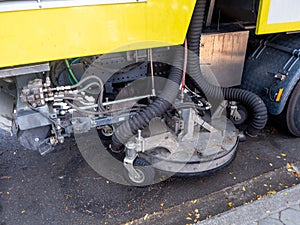 Car for cleaning roads with round brushes on a city street