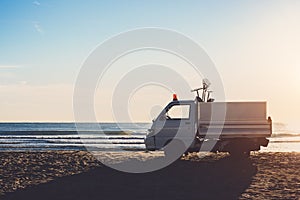 Car of cleaning service on the beach at sunrise