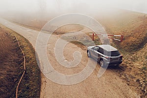 Car on the countryside road in foggy morning, high angle view
