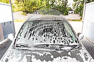 the car is covered with foam at a self-service car wash. Close-up of a windshield