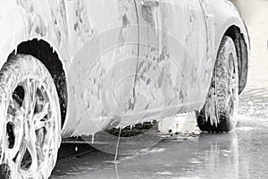 The car is covered with foam at a self-service car wash. Man washes foam machine. Carwash. Washing machine at the station