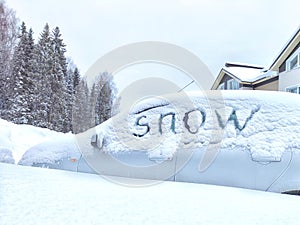 The car is covered with snow and the inscription snow on the glass. Extreme snowfall, severe weather. Travel, tourism