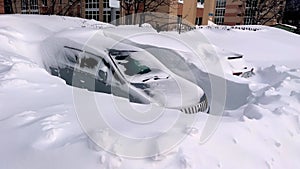 Car covered in snow parked on parking lot in winter season. Parked car covered with snow after blizzard. Car buried