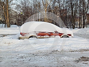 A car covered in snow in a parking lot.