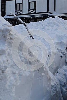 Car covered in snow and a windshield wiper