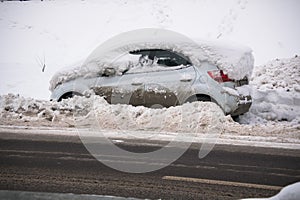 The car, covered with thick layer of snow and mud, on the roadway.