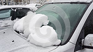 The car, covered with thick layer of snow. Negative consequence of heavy snowfalls. Close-up shot of a car`s windscreen wiper