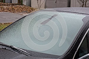 The car, covered with thick layer of snow. Negative consequence of heavy snowfalls. Close-up shot of a car`s windscreen wiper