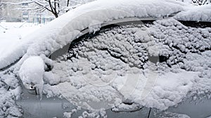 The car, covered with thick layer of snow. Negative consequence of heavy snowfalls.