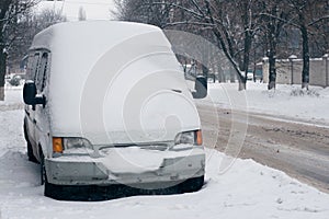 Car covered with white snow in the city. Minibus under the snow. Sleet slush, ice covering on the roads, and southeastern