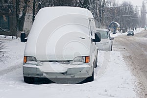 Car covered with white snow in the city. Minibus under the snow. Sleet slush, ice covering on the roads, and southeastern