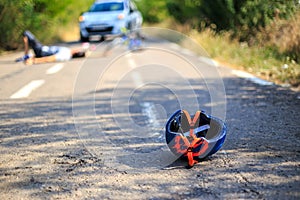 Car crash with the injured person and bicycle helmet on road