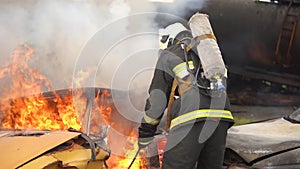 On the Car Crash Traffic Accident Scene: A fire rescue worker professionally extinguishes a fire in a car with a fire