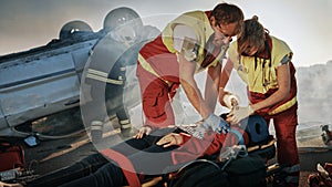 On the Car Crash Traffic Accident Scene: Paramedics Saving Life of a Female Victim who is Lying on