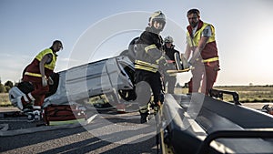 On the Car Crash Traffic Accident Scene: Rescue Team of Firefighters Pull Female Victim out of Rol