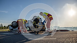 On the Car Crash Traffic Accident Scene: Team of Paramedics and Firefighters Rescue Injured People