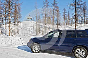 Car crosses the line of northern polar circle along winter road near the sign `Polar Circle`