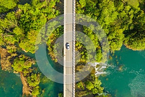 Car crossing road bridge over Mreznica river in Croatia, overhead shot of countryside landscape