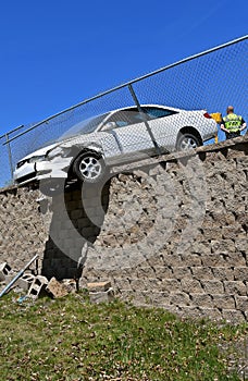 Car in danger of rolling off a retaining wall