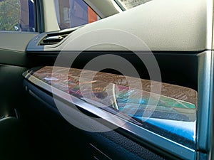 Car dashboard. Air conditioning system and airbag panel. Interior detail with carbon trim elements with sun reflection.