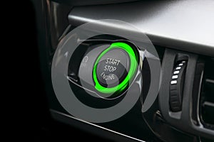 Car dashboard with focus on green engine start stop button. Car interior details. Car detailing.