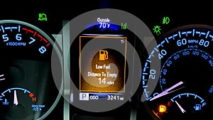 Car dashboard with low fuel warning displayed on the monitor. High fuel prices concept with a modern car dash, vibrant colors.