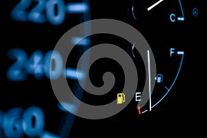 Car dashboard shows low fuel warning light, selective focus