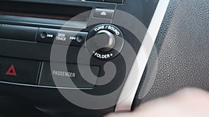 Car dashboard volume knob. Driver's hand adjusts volume, sound control of car radio