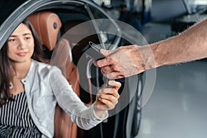 Car dealer is giving key for a new car to young woman