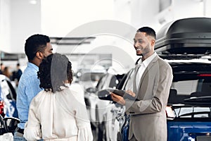 Car Dealer Man Selling Auto Talking With Customers In Dealership photo