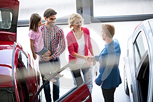 Car dealer offering a car to family photo