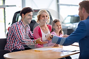 Car dealer selling new automobile to young family with child