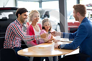 Car dealer selling new car to young family