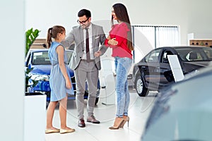 Car dealer selling new vehicle to beautiful young family