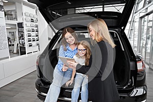 Female car dealer communicating with clients in showroom. photo