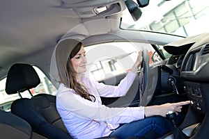 Car dealership advice - young woman sitting and testing in a new