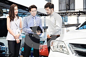 Car Dealership. The Asian Salesman woman and man checking the list with the middle east customer before hand over.