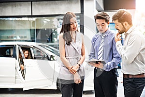 Car Dealership. The Asian Salesman woman and man checking the list with the middle east customer before hand over.