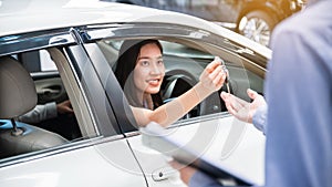 Car Dealership. The Asian woman receiving a car key with a smile form the salesman before hand over. Auto Leasing Business