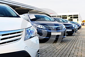 Car dealership - many vehicles parked for sale in a row photo