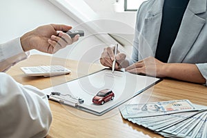 Car dealership provides advice about insurance details and car rental information and delivers the keys after signing the rental